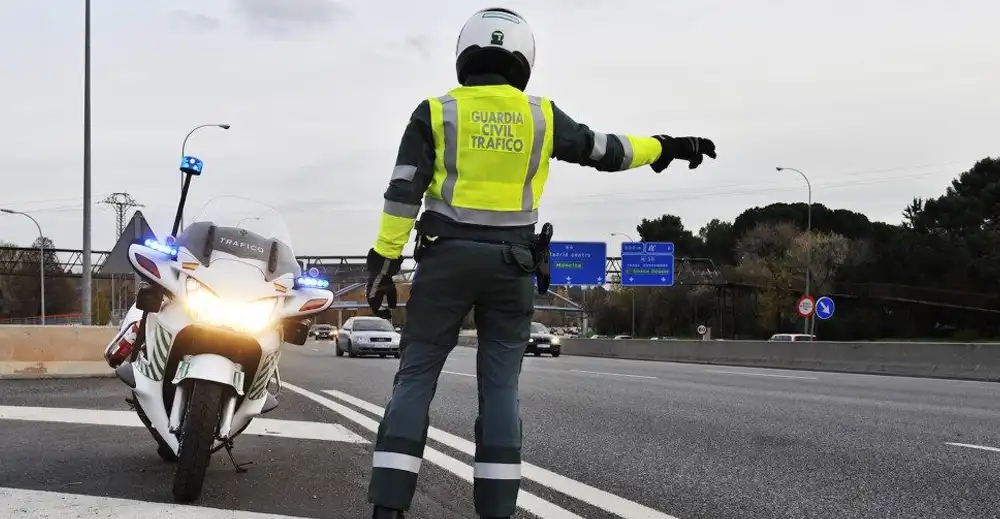 guardia civil de trafico con moto estacionada vigilando los coches